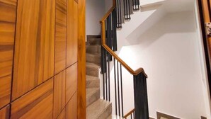 A wooden staircase with a black railing and a white wall. - VINANDA (New Delhi)