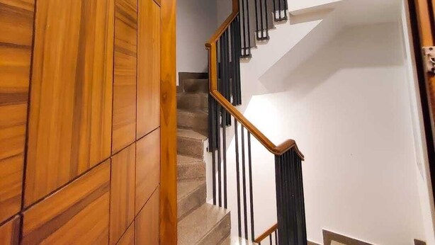 A wooden staircase with a black railing and a white wall. - VINANDA (New Delhi)