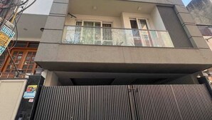 A multi-story building with a gated entrance, balconies, and visible power lines. - VINANDA (New Delhi)