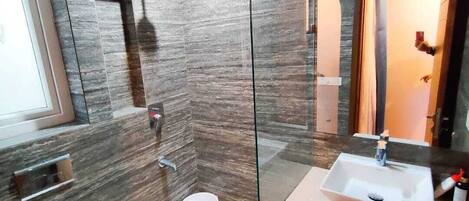 Un baño moderno con cabina de ducha de vidrio, un lavamanos blanco y un inodoro.