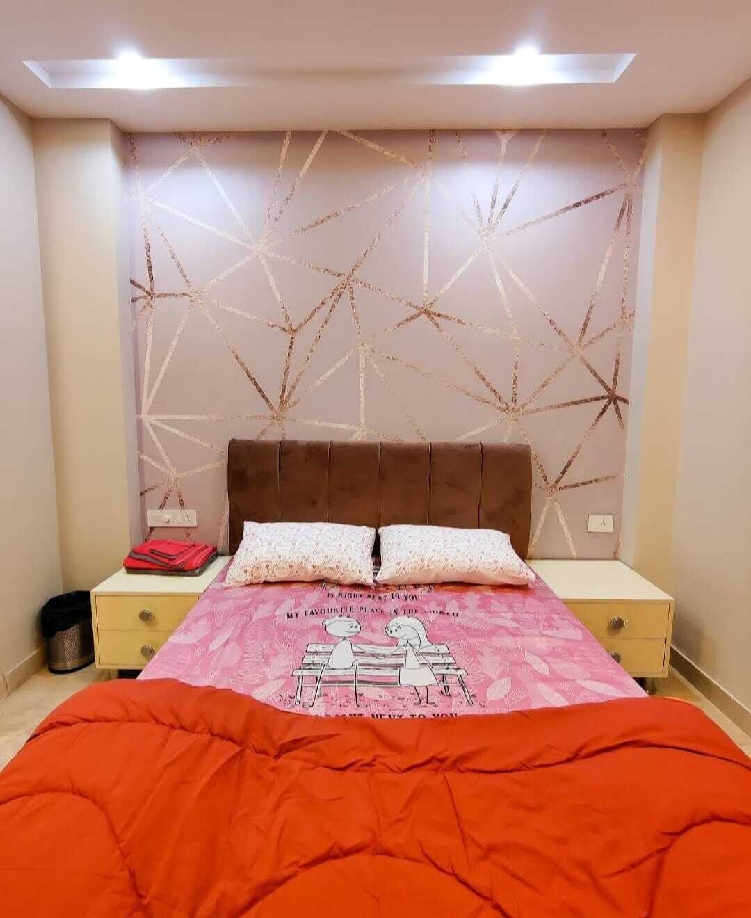 A bedroom with a bed, two pillows, a nightstand, and a wall with a geometric pattern.