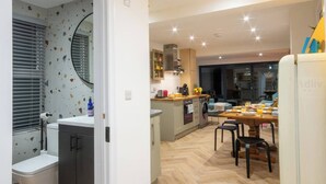 A modern kitchen with a central island, built-in appliances, and a dining area with a wooden table and chairs. - Modern Margate Maisonette close to the beach by Adliv (Margate)