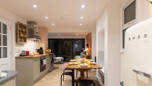 A modern kitchen with a dining area, a built-in oven, and a refrigerator. - Modern Margate Maisonette close to the beach by Adliv (Margate)