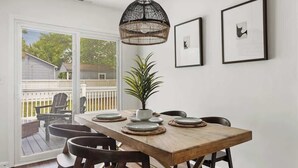 Un coin repas avec une table en bois, des chaises, un luminaire suspendu et des œuvres d’art encadrées accrochées au mur.