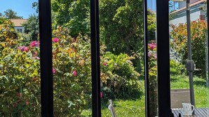 Ein Wintergarten mit Blick auf einen Garten, eine Holzterrasse und eine Patio mit Gartenmöbeln.