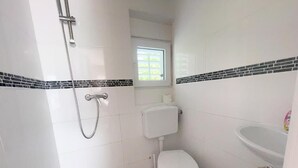 Et lille, rent badeværelse med toilet, vask og brusebad.