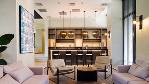 A modern living room with a sofa, armchairs, a coffee table, and a kitchen area with bar stools and pendant lights. - Retreat in Providencia | Steps to Attractions (Providencia)