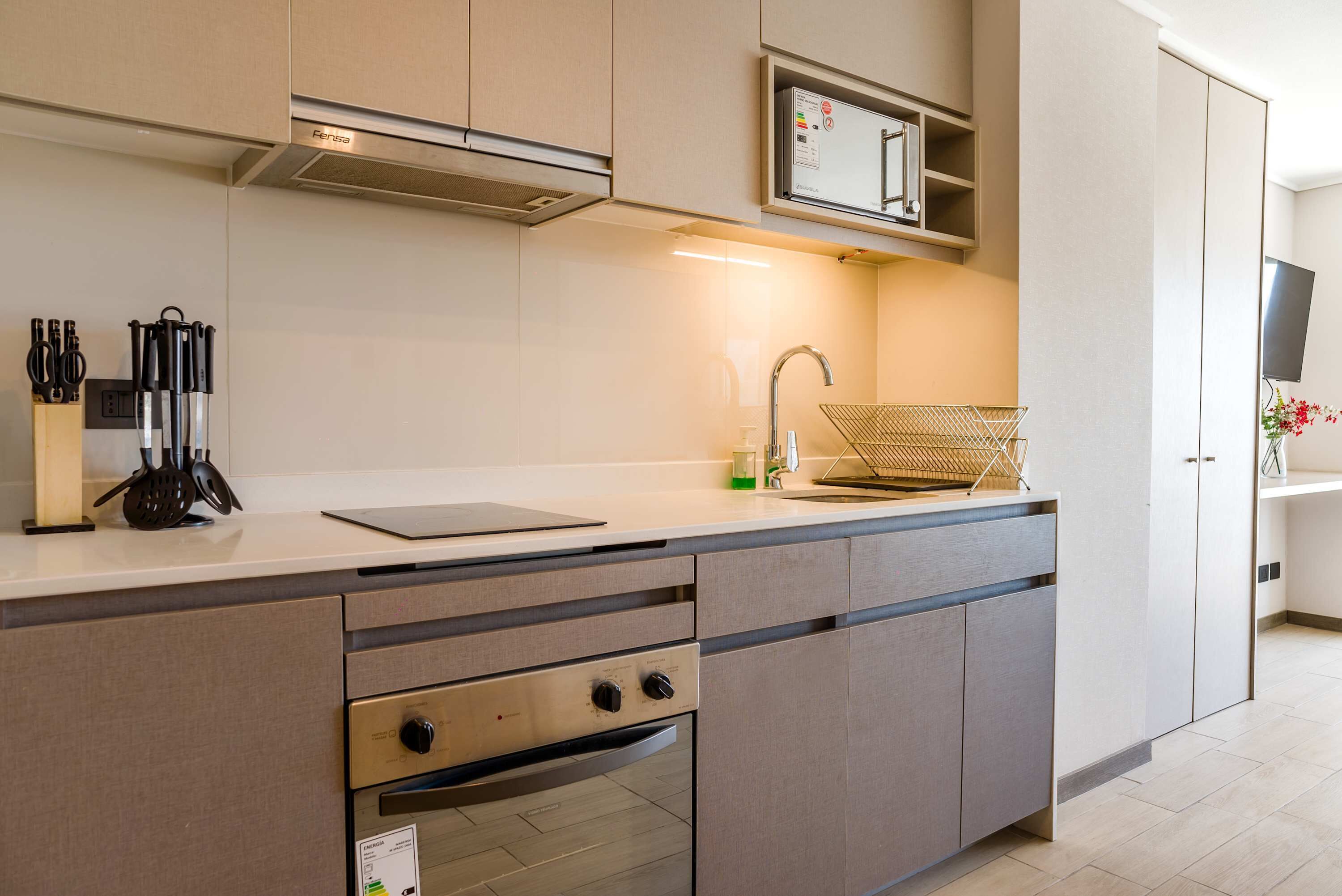 A modern kitchen with a built-in oven, a sink, and a microwave.