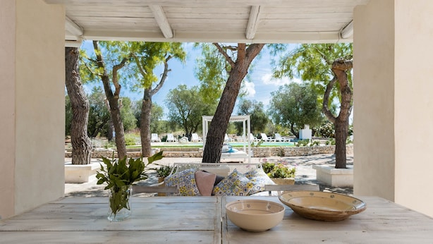 A wooden table with a vase and a bowl, overlooking a garden with trees and a gazebo. - Villa Thea - Charming House (Carovigno)