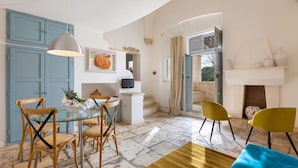 A dining area with a glass table and chairs, a blue cabinet, and a fireplace with a mantel. - Villa Thea - Charming House (Carovigno)
