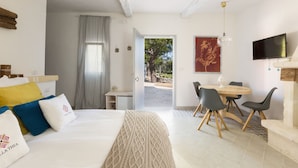 A hotel room with a bed, a desk, a dining table with chairs, and a TV. - Villa Thea - Charming House (Carovigno)