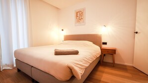 Uma cama bem arrumada com cabeceira, mesa de cabeceira e luminária na parede.