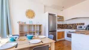 A modern kitchen with a built-in refrigerator, wooden cabinets, and a microwave. - Comfort & Charm – 1-Min Walk to the Sea (Valras-Plage)