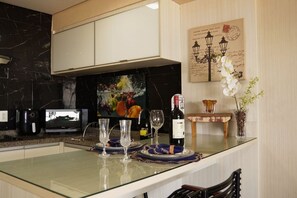 A modern kitchen with a marble backsplash, a flat-screen TV, and a wine bottle on the counter. - Beira Mar Fortaleza Landscape Luxo (Fortaleza)
