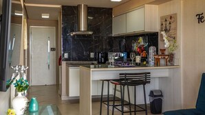 Une cuisine moderne avec un dosseret en marbre, des appareils en acier inoxydable et un coin bar avec des tabourets.