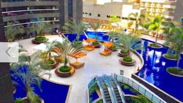 Een moderne hotelatrium met een centraal gelegen zwembad, omringd door palmbomen en zitgedeeltes.