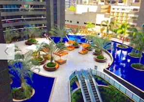 A modern hotel atrium with a central pool, surrounded by palm trees and seating areas. - Beira Mar Fortaleza Landscape Luxo (Fortaleza)