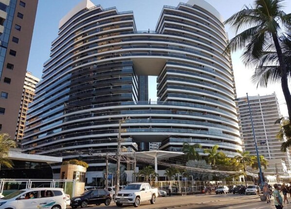 Un hôtel moderne à plusieurs étages, doté d’une façade incurvée et d’un atrium central.