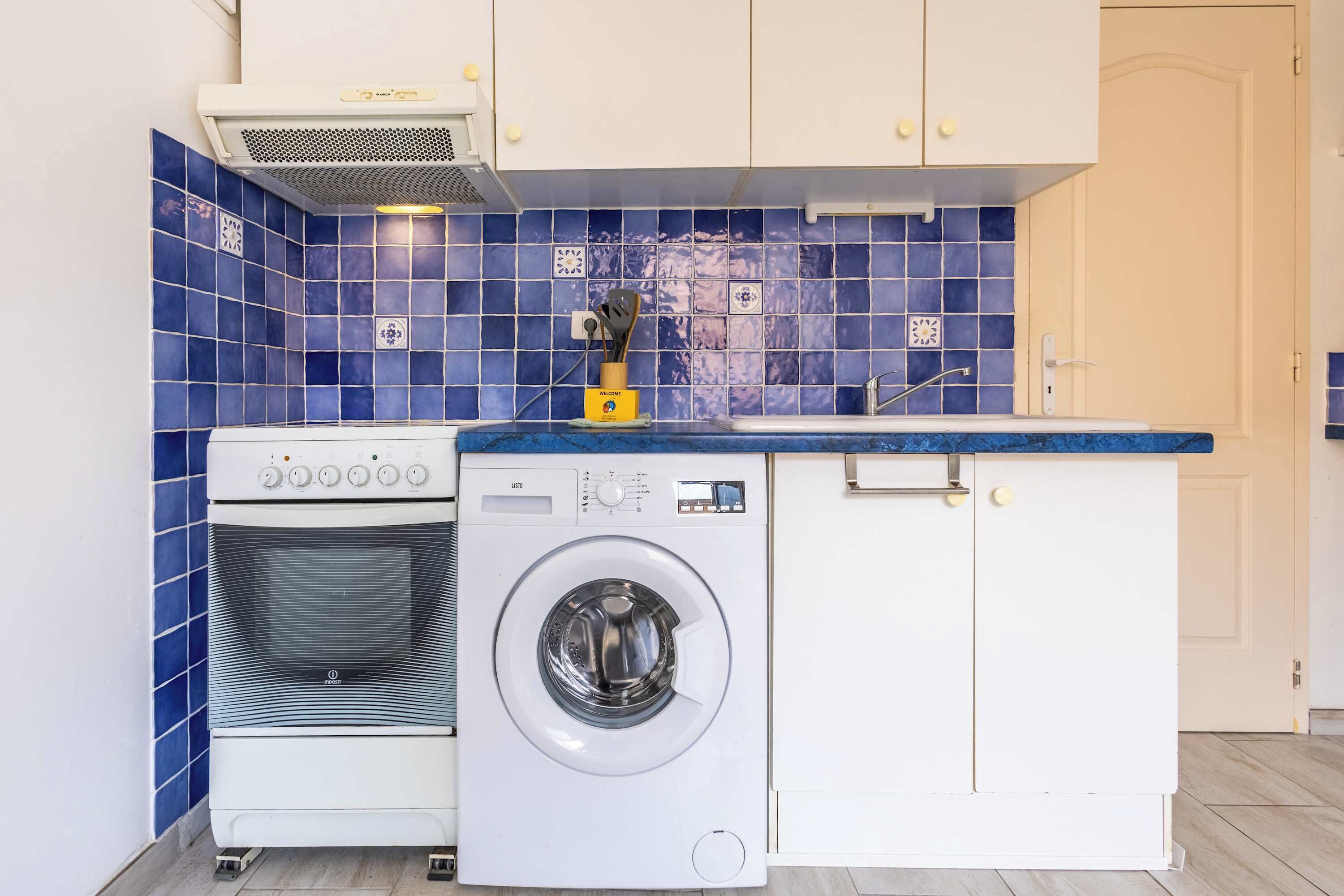 A compact kitchen with a washing machine, a stove, and a sink.