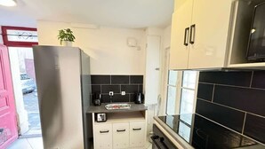 A compact kitchen with a refrigerator, stove, microwave, and a small countertop with a toaster. - Orb Room – 1st Floor (Béziers)