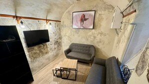 Ein rustikaler Raum mit einer Couch, einem kleinen Holztisch und einem schwarzen Schrank.