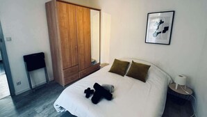 Un dormitorio con una cama grande, un armario de madera y un cuadro en la pared.
