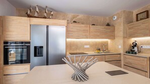 A modern kitchen with wooden cabinets, stainless steel appliances, and a central island. - Beachfront Apartment w/ Terrace, Hot Tub & Parking (Valras-Plage)