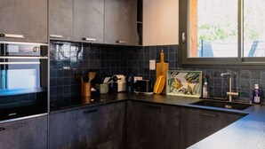 Une cuisine moderne avec des meubles de couleur sombre, un grand îlot central et un luminaire suspendu.