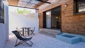 Une terrasse extérieure avec une table et des chaises, une plateforme en bois et un espace salon abrité.