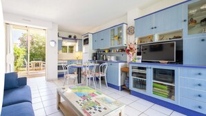 Una cucina moderna con mobili blu, una zona pranzo con sedie e un divano in un soggiorno.