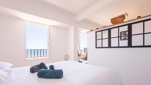 Une chambre d’hôtel avec un lit, une fenêtre, une étagère fixée au mur et une porte.