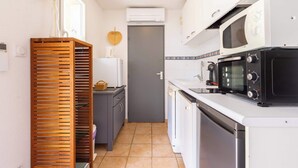 A compact kitchen with a microwave, oven, and dishwasher. - T2 with Pool, Terrace & Parking (Valras-Plage)