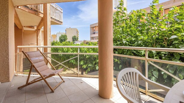 A balcony with a chair, a table, and a railing. - T2 with Pool, Terrace & Parking (Valras-Plage)