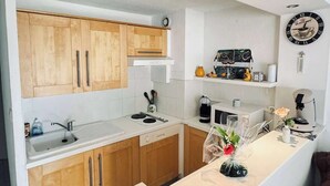 Een moderne keuken met houten kastjes, een wit aanrecht, een spoelbak, een fornuis en een koffieapparaat.