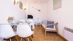 A dining area with a table set for two, a television, and a lounge bar sign.