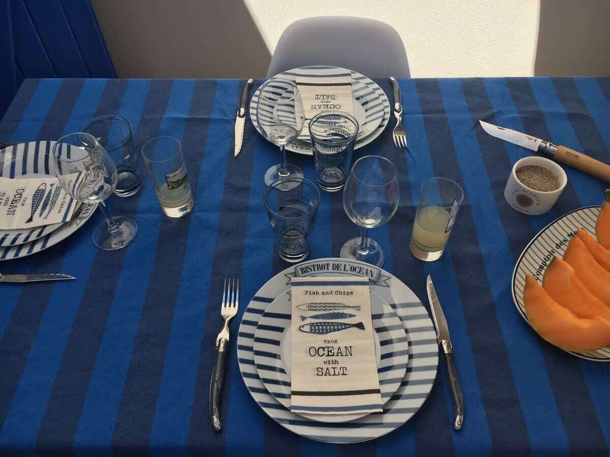 A table set with blue and white striped tablecloth, plates labeled 'BISTROT DE L'OCEAN,' and a menu titled 'Fish and Chips from Ocean with Salt.'