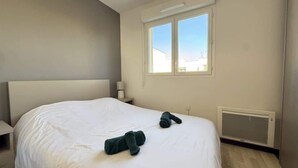 Ein Schlafzimmer mit einem großen Bett, einem Fenster, einem Nachttisch und einer Heizung.