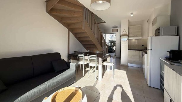 Ein moderner Wohnraum mit Treppe, Essbereich und Küche.