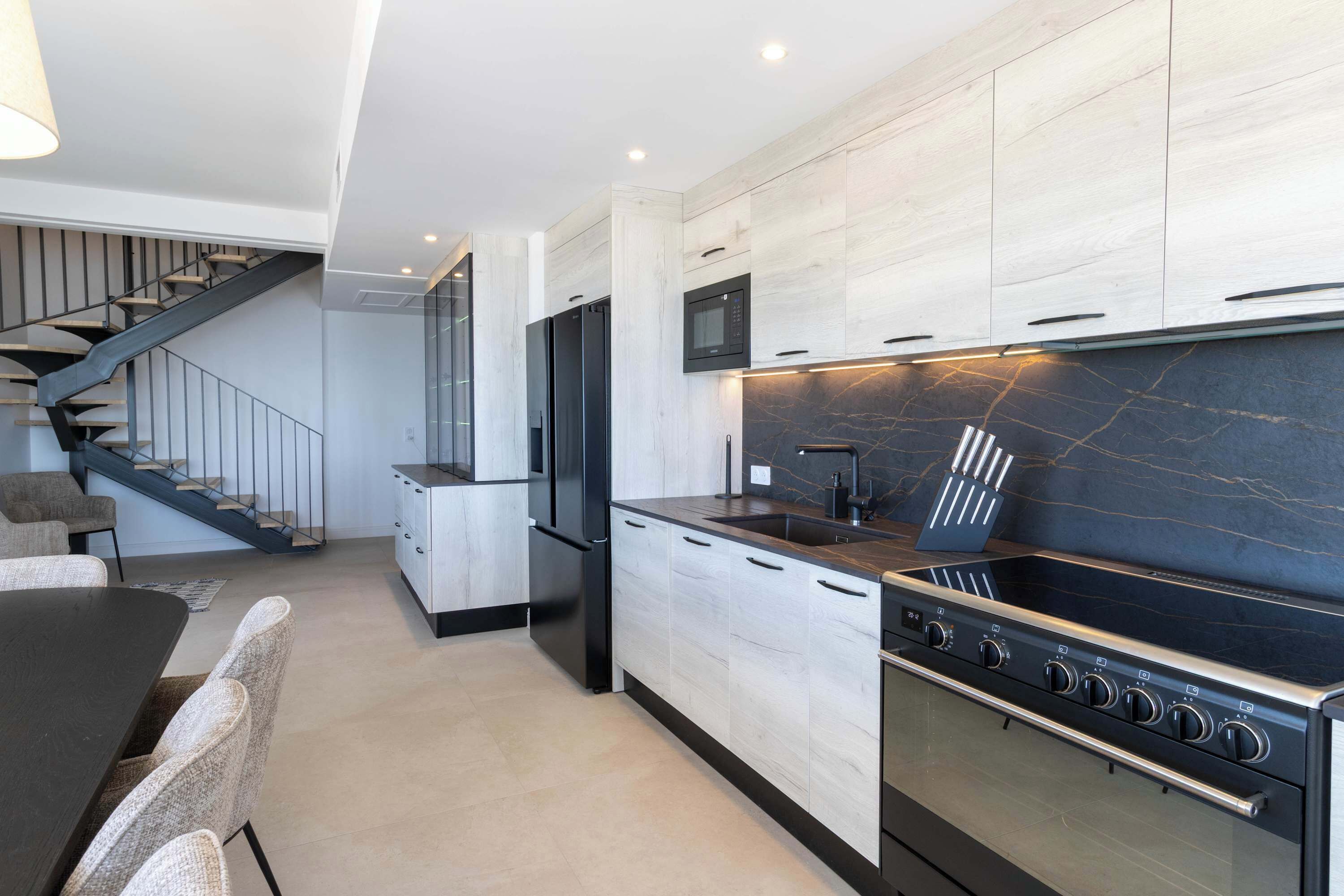 A modern kitchen with a built-in oven, microwave, and stainless steel range.