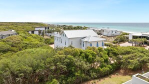 A coastal property with a large white house, multiple smaller buildings, and lush greenery.
