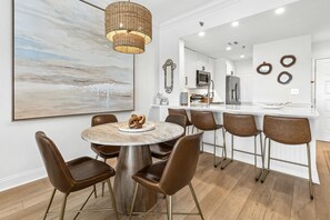 A modern kitchen with white cabinets, stainless steel appliances, and a bar area with stools. - 2 Bedroom Beach Manor condo on the 6th Floor at Tops’l Resort with Sandestin Resort Perks!! (Miramar Beach)