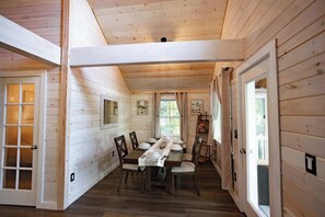 A dining area with a wooden table set for six, flanked by two doors leading to other rooms. - Gables End Escape Lakefront Dock Kayaks (Belgrade)