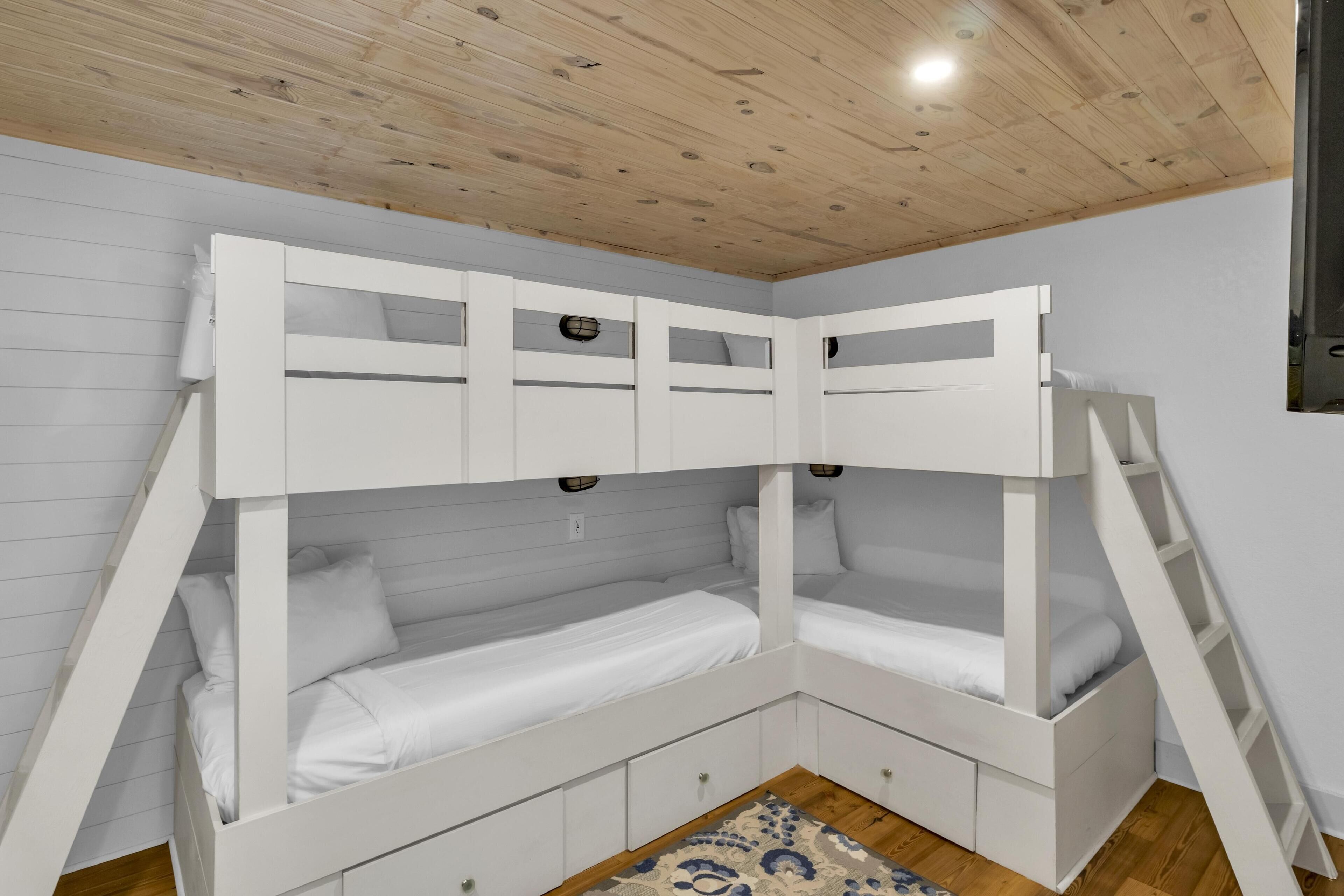 Ein Etagenbett mit Stauraumschubladen, einer Holzbalkendecke und einem gemusterten Teppich.