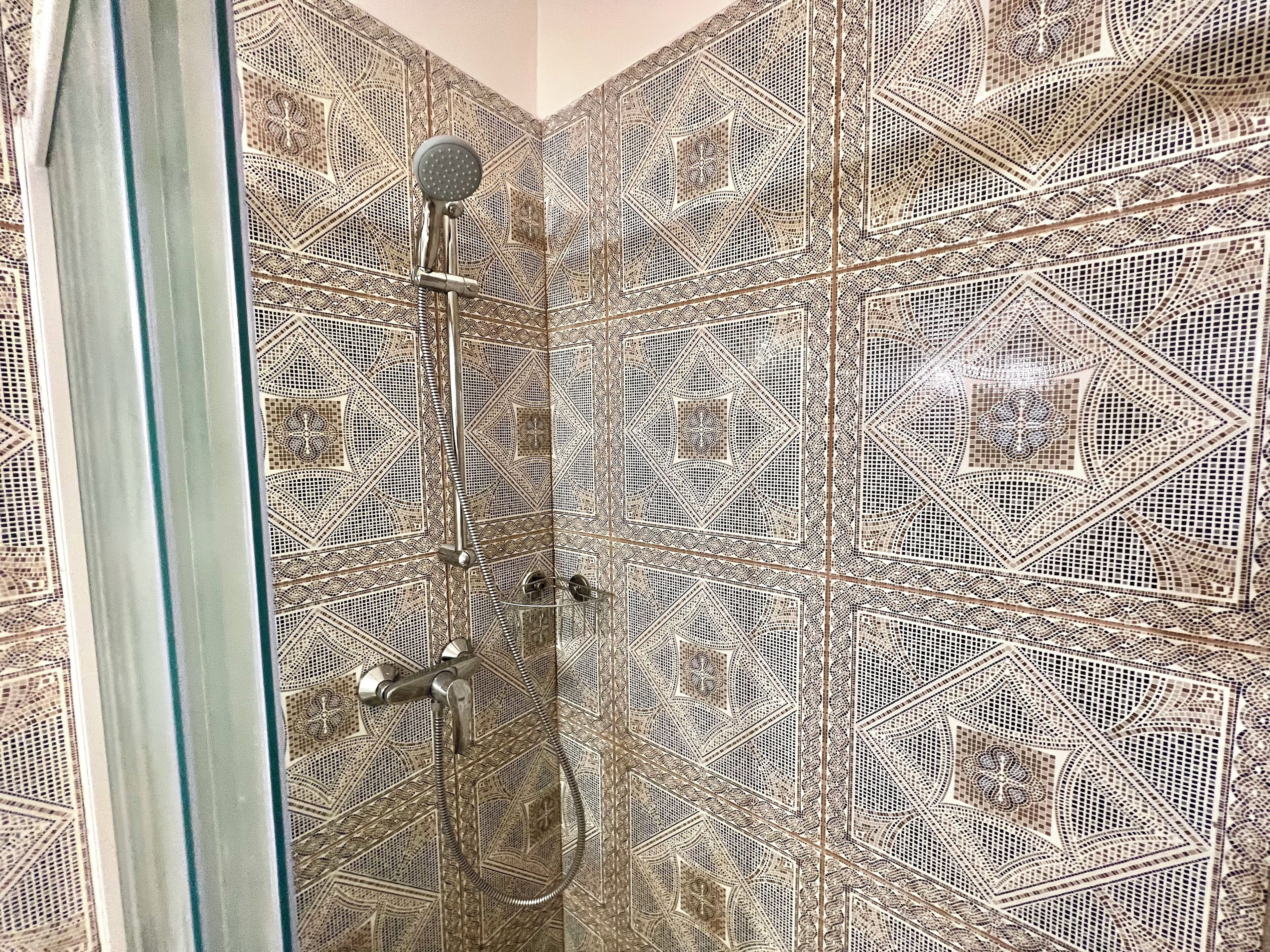 Een douche met een handdouche en een apart handmatige douchestraal.