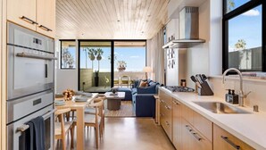 Een moderne keuken met inbouwapparatuur, een eethoek en uitzicht op palmbomen.