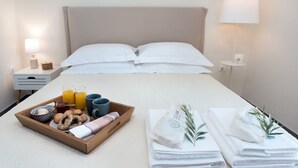 Een net opgemaakt bed met witte lakens, een dienblad met ontbijtartikelen en handdoeken aan de zijkant.