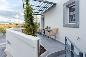 Un pati exterior modern amb un teulat de vidre, una taula amb caires i una petita zona de jardí.