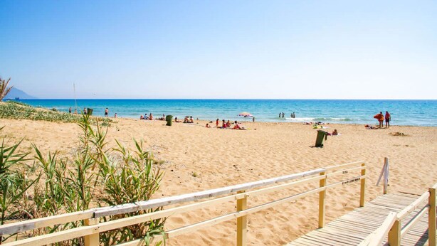 Une plage de sable avec une promenade en bois qui mène à l’eau.