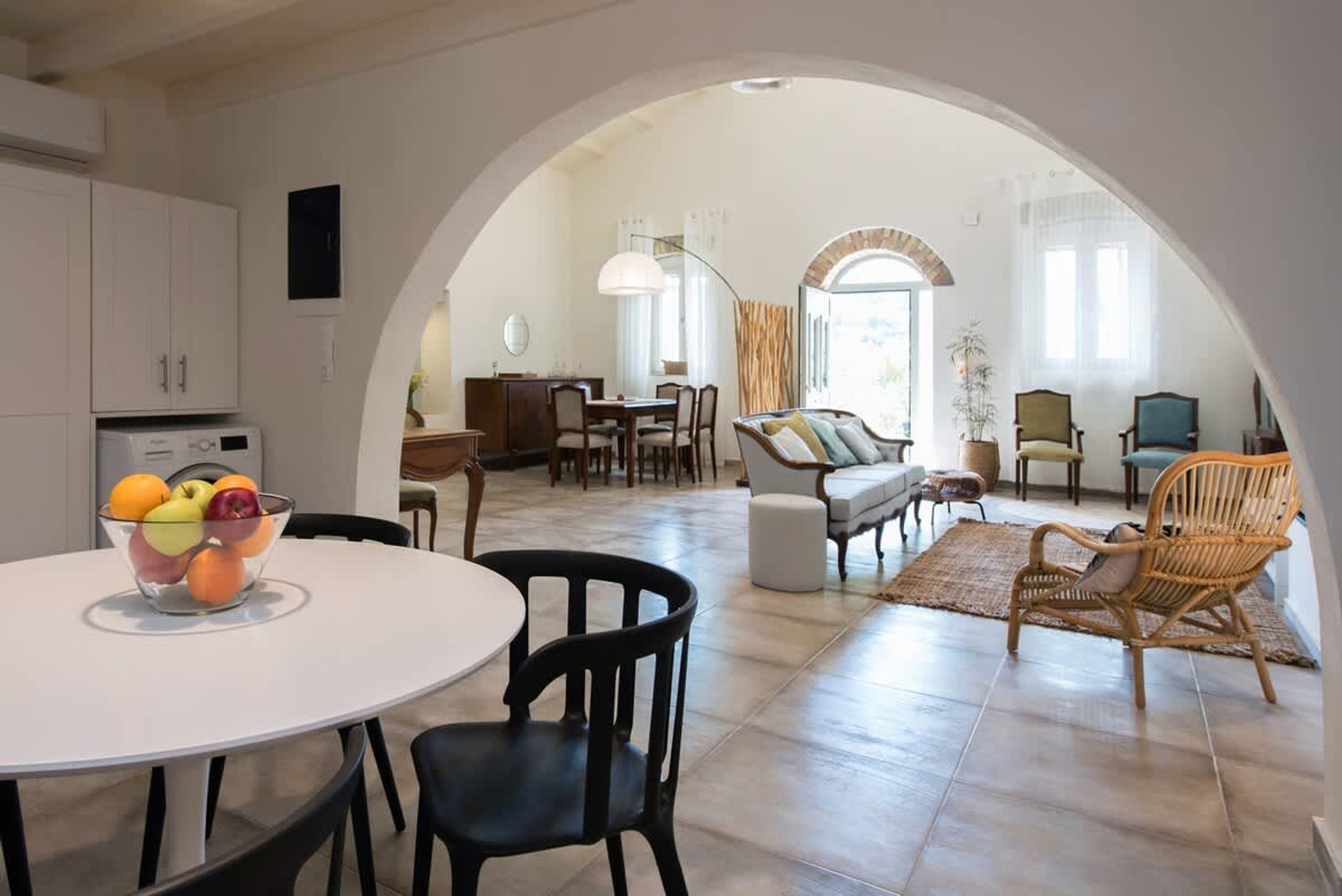 Un grand espace de vie comprenant un coin repas avec une table et des chaises, et une cuisine en arrière-plan.