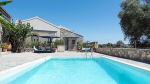 Une piscine avec un mur en pierre et une maison en arrière-plan.